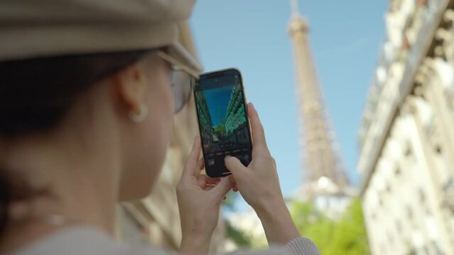 Happy tourist taking a photo of the Eiffel Tower standing on a famous Parisian street
