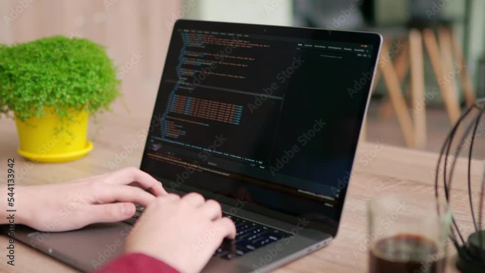 Wall mural close up of freelancer's hands typing code on laptop keyboard. camera slides around developer's fige