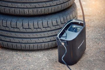Air compressor, portable tire inflator. Inflating summer wheels with portable air pump outdoor...