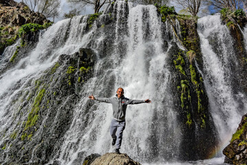 A man near the Shaki waterfall, with a height of 18 m. It is located in the Syunik region of Armenia, near the city of Goris. May 5, 2019