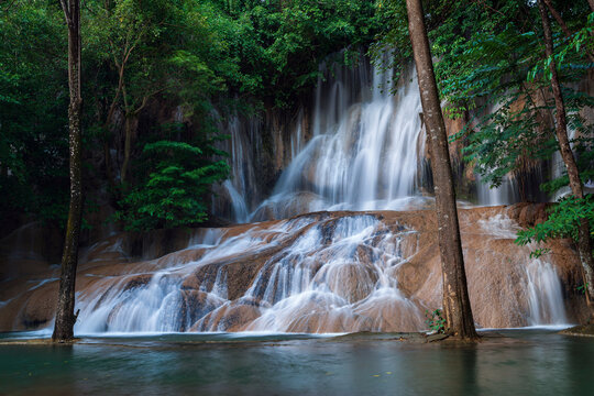 Shot from iconic Sai yok noi waterfall that flows through rock crevices down to a large emerald pool with green forest in Sai yok national park, Thailand. © Narupon