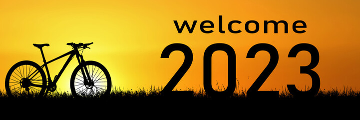 Fototapeta na wymiar Welcome concept 2023 and happy new year. Cyclist silhouette in the meadow