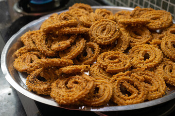 Homemade crunchy Diwali snack arranged in plate. Indian traditional snack, deep fry, chakli, muruku, murkoo, vegetarian, spicy, namkeen, chiwda, faral, crunchy, tasty, cholesterol, chakali, murukku.