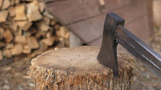 The wood chopper sticks out in wooden hemp. Woodworking. Ax to chop wood. Rusty but very sharp forester's axor carpenter's axe. Closeup of axe cutting log while other logs laying in the background.
