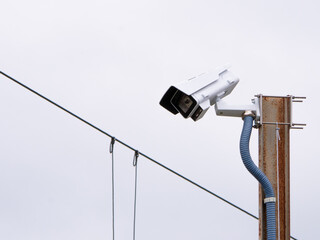 Downward facing security surveillance camera placed on a rusty metal pole at high altitude and...
