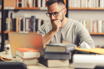 Young man studying in the campus library. 
