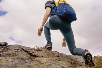 Fit woman athlete hiking in mountains over rocky trails. Low angle view