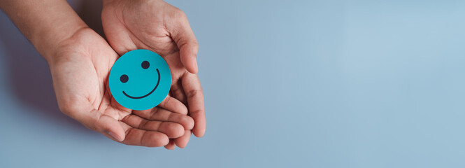 Hands holding blue happy smile face, good feedback rating, positive customer review, experience,...