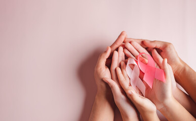 hands of people holding pink ribbons on pink background, Breast cancer awareness, world cancer day, national cancer survivor day in february concept.