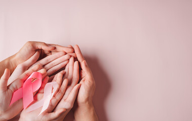 hands of people holding pink ribbons on pink background, Breast cancer awareness, world cancer day,...