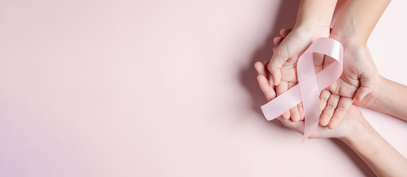 Hands Holding Pink Ribbons On Pink Background, Breast Cancer Awareness, World Cancer Day, National Cancer Survivor Day In February Concept.