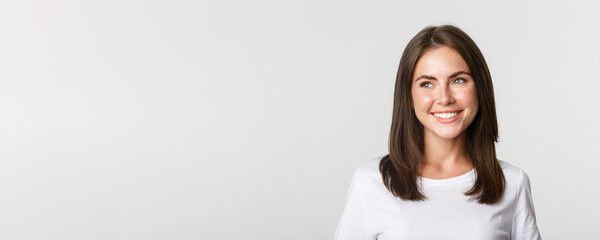 Portrait of attractive thoughtful girl smiling and looking left, white background