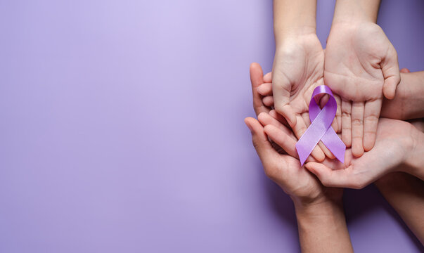 hands holding purple ribbons, Alzheimer's disease, Pancreatic cancer, Epilepsy awareness, world cancer day on a purple colored background, World Cancer Day concept