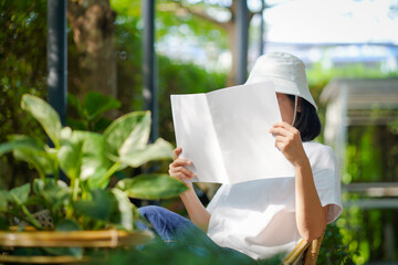 teenage gril holding and reading book or magazine at garden.