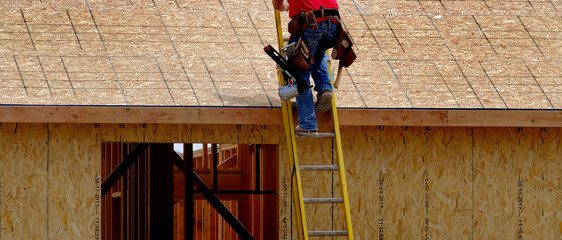 Construction Worker Climbing Up Ladder on Home Being Built