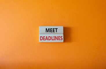 Naklejka premium Meet Deadlines symbol. Concept word Meet Deadlines on wooden blocks. Beautiful orange background. Business and Meet Deadlines concept. Copy space