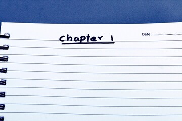 White notebook on blue background with text CHAPTER 1, showing the positive intent of a writer to write the first page of a book.