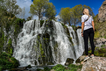 A young girl near the Shaki waterfall, with a height of 18 m. It is located in the Syunik region of Armenia, near the city of Goris. May 5, 2019