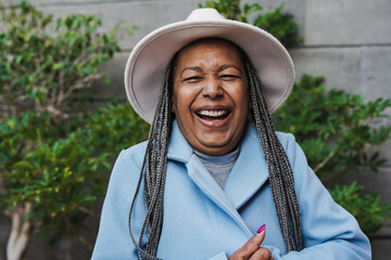 Happy senior african woman smiling on camera while wearing trendy hat during winter time