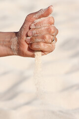 Sand running through hands on beach