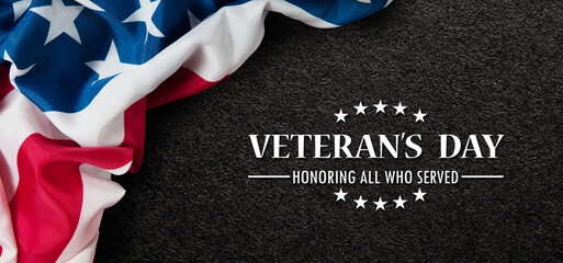 Fototapeta na wymiar Closeup of American flag with Text Veterans Day Honoring All Who Served on black textured background. American holiday banner.