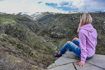 Naklejka na ściany i meble A girl on mount Aragats near the 7th-century Amberd fortress, at the confluence of the Arkashen and Amberd rivers, Armenia 2019