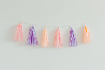 Tissue paper tassel garland. Pastel colors on the white background. Decoration for party. Minimalist style, copy space