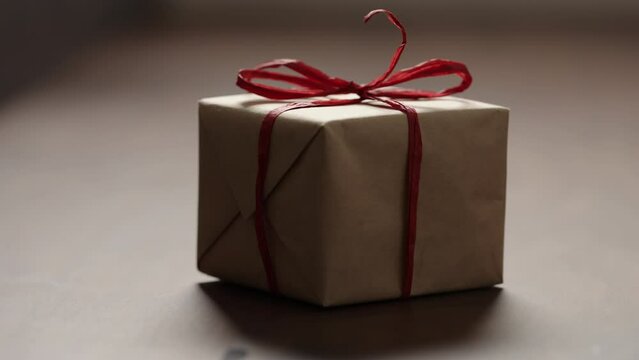 Slide shot of brown paper gift box with red bow on wood table