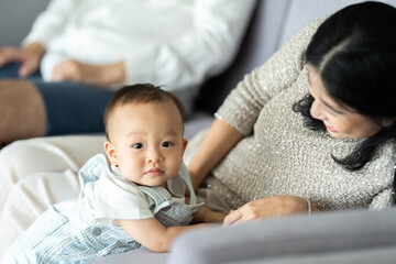 Fototapeta premium Cute little baby toddler playing and enjoying while in the arms of young mother hugging at home