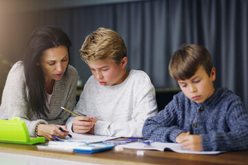 Education is up to all of us. Shot of a mother helping her sons with their homework.