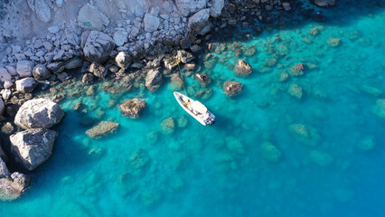 Aerial drone top down photo of white inflatable rib speed boat anchored in tropical exotic rocky bay with emerald sea