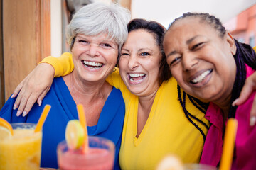 Multiethnic senior woman having fun drinking healthy smoothies at brunch restaurant - Focus on...