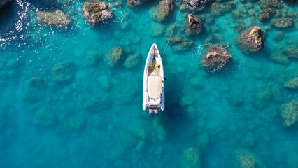 Aerial drone top down photo of white inflatable rib speed boat anchored in tropical exotic rocky...