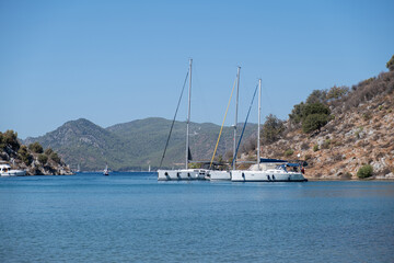 Beautiful bay with sailing boats, yachts in turquoise sea and mountains, luxury holidays or sailing regata sports.