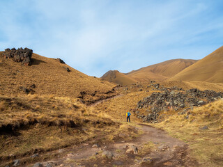 Solo trekking in the Caucasus mountain. Man with a backpack is climbing heavily on a mountain trail. Adventure solo traveling lifestyle concept, active weekend vacation on the wild nature.