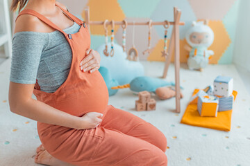 Pregnant woman belly with Baby activity gym play, toys and playmat in nursery or playroom. Pregnancy concept and home nusery planning and decoration concept photo