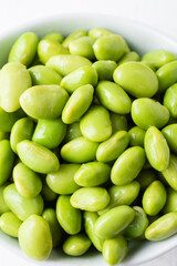 Macro closeup of edamame beans in white bowl, vertical