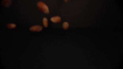 Macro Close Up view of Hazelnuts falling in a black environement in 4K slow motion