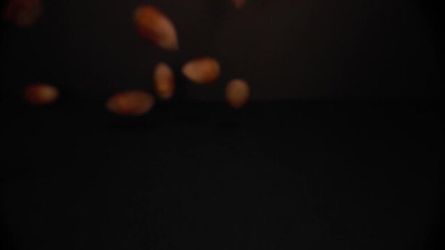 Macro Close Up view of Hazelnuts falling in a black environement in 4K slow motion