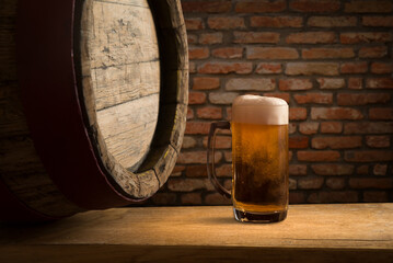 Oktoberfest beer barrel and beer glasses with wheat and hops on wooden table. High quality photo
