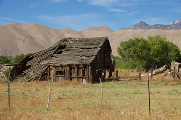 vintage redwood barn with collapsed roof in an open field