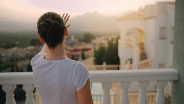 Woman goes out on the terrace looking out over sunset.