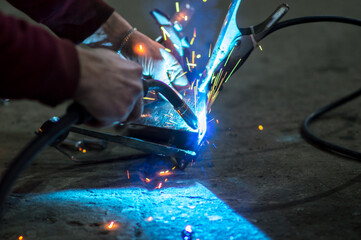 Obraz premium welder in the dark performs welding work on the metal with a welding machine 
