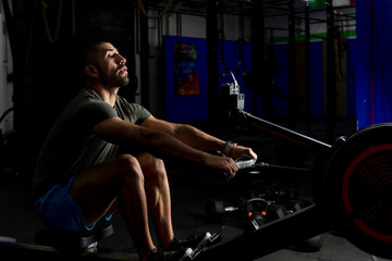 Fototapeta na wymiar low light shot of an athlete rowing in a gym