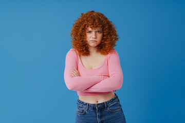 European woman with red curly hair frowning and looking at camera