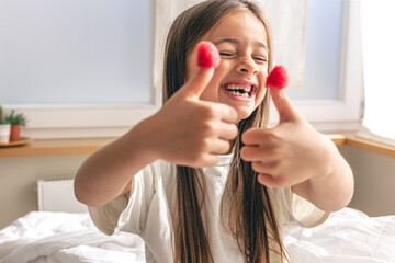 Funny little girl with raspberries on her fingers in bed in the morning.