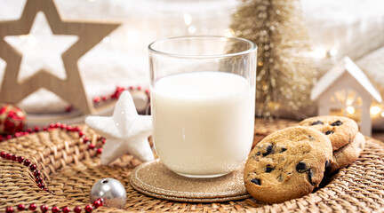 Christmas cookies and glass of milk for Santa on holiday blurred background.