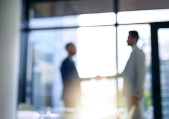 Building business relationships. Blurred shot of two businessmen shaking hands in a modern office.