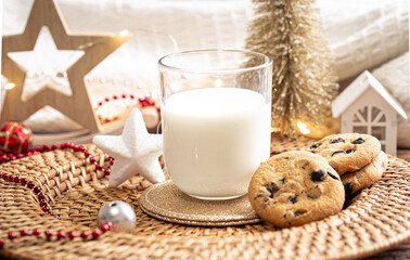 Christmas cookies and glass of milk for Santa on holiday blurred background.