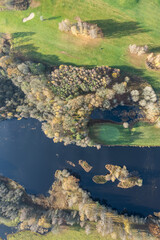 Aerial panoramic view of beautiful autumn morning, golf course, river, multicolored trees and green grass, warm sunlight, shadows